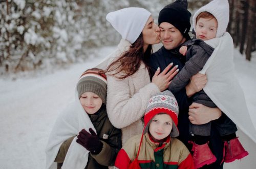 A joyful family enjoying a snowy day in a forest, wrapped in warm clothing.